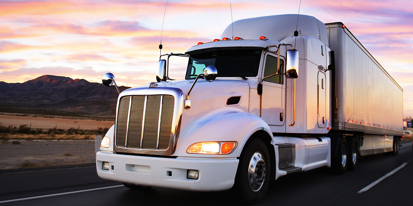 Semi truck driving on a road at sunset